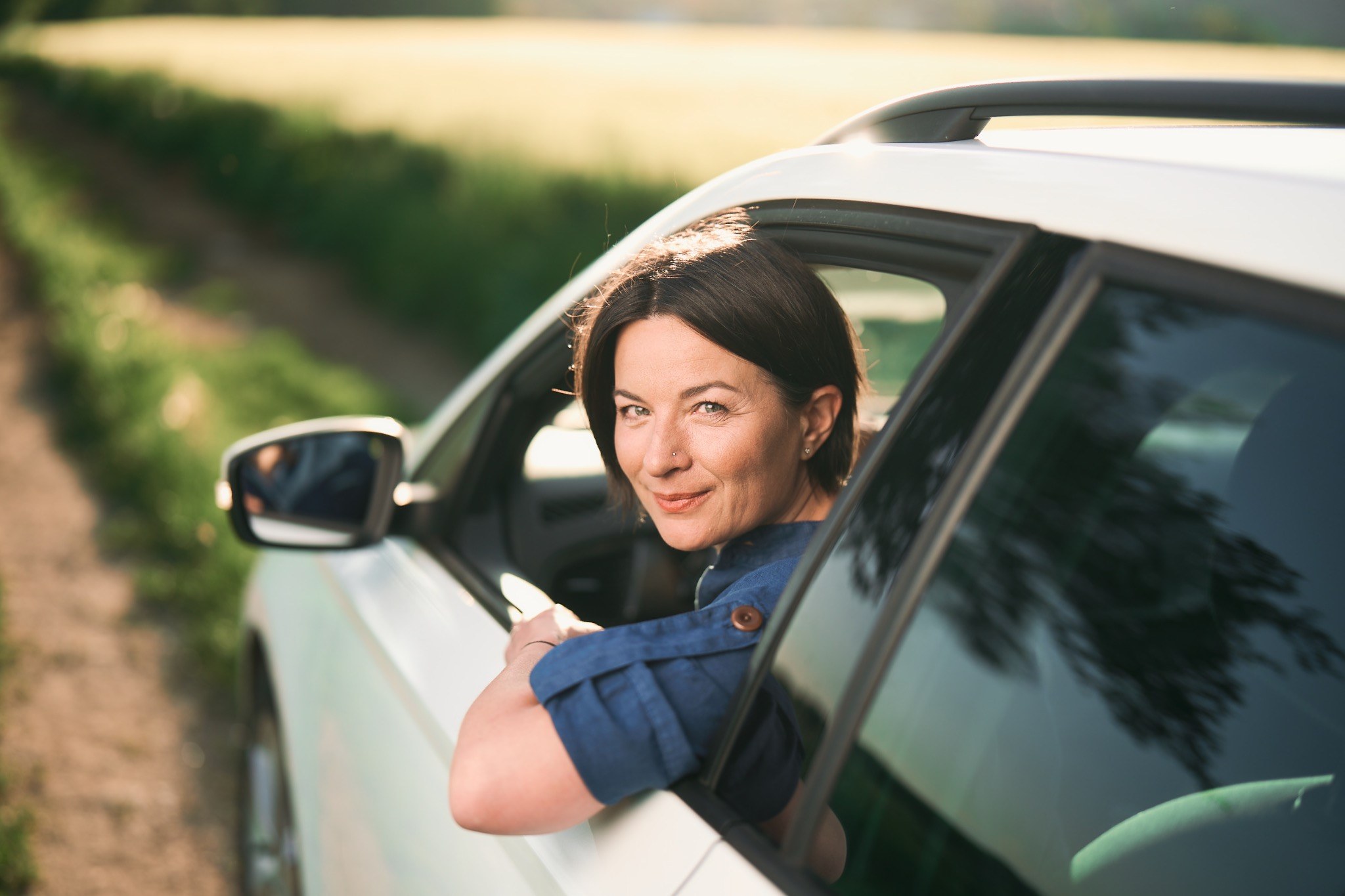 Brenda Stys sitzt entspannt im Auto und blickt aus dem geöffneten Fenster
